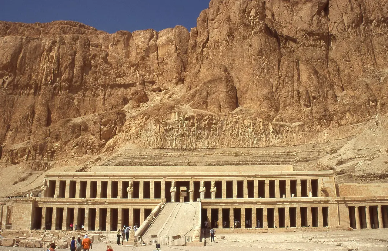 Panoramic view of Luxor's West Bank, featuring the Valley of the Kings, the Mortuary Temple of Hatshepsut, and the Colossi of Memnon under a sunny sky.