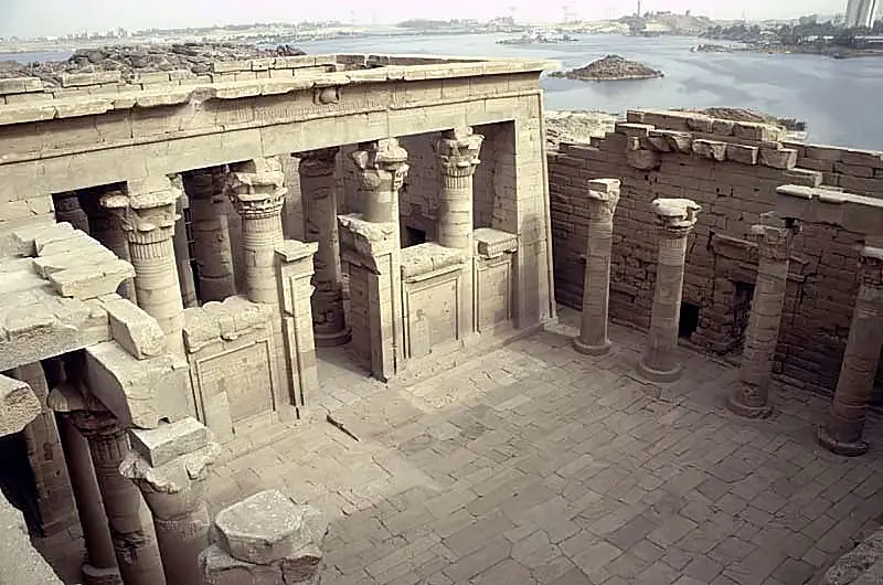 A panoramic view of the High Dam of Aswan with the vast Nile River reservoir, alongside the ancient Kalabsha Temple carved into the stone.