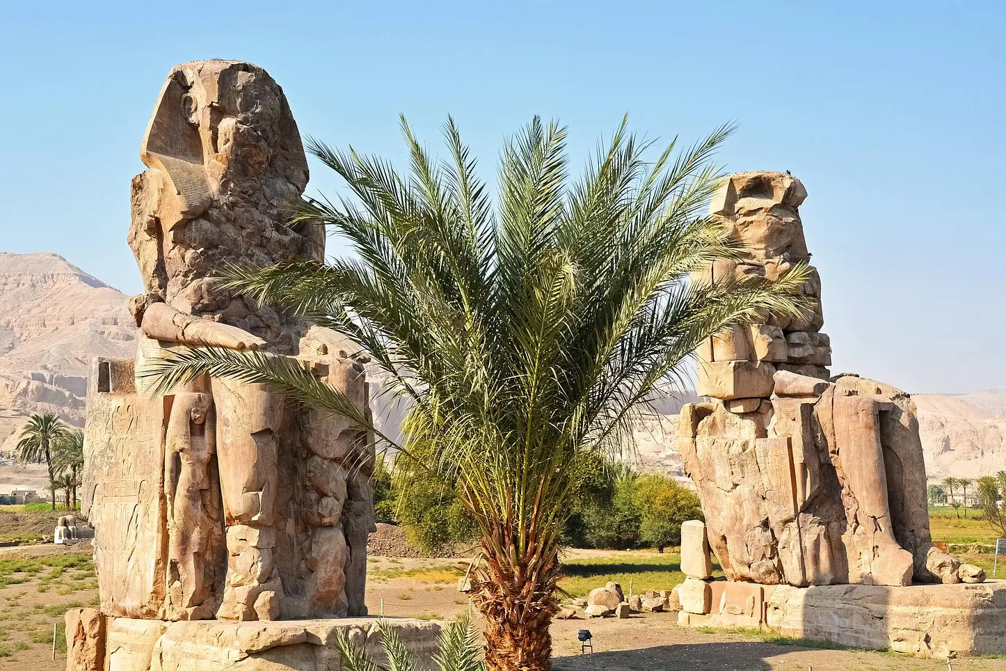 Tourists exploring the Temple of Karnak in Luxor, with towering columns and hieroglyphic carvings under a clear blue sky.