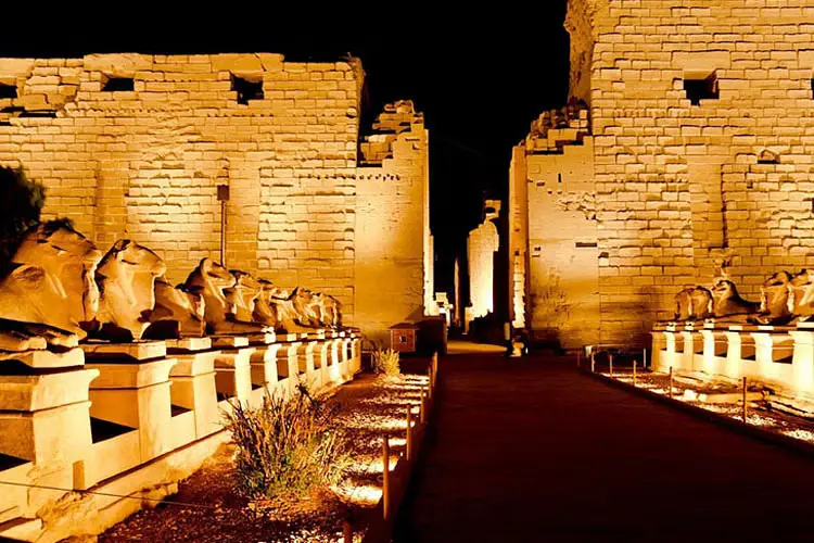 The illuminated Karnak Temple complex at night, with vibrant light projections and a narration echoing through its ancient columns.