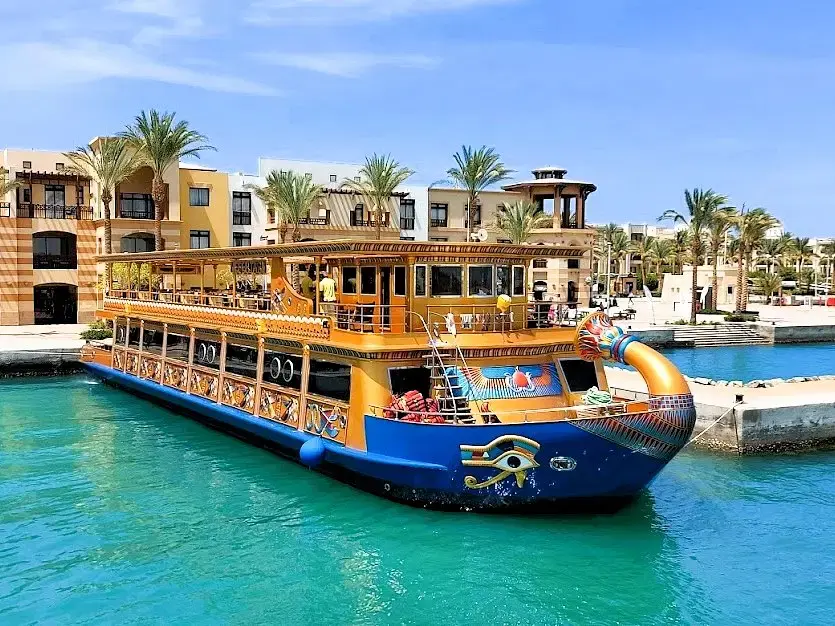 A luxury glass-bottom boat cruising through the clear waters of the Red Sea, with passengers viewing vibrant coral reefs and marine life beneath the surface.