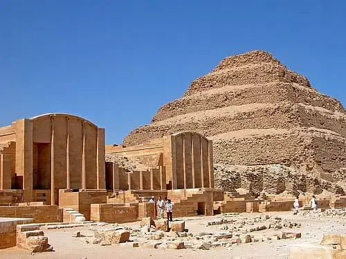 The Great Pyramid of Giza towering against the blue sky, with the Step Pyramid of Djoser in the background and the Bent Pyramid of Dahshur in the distance.